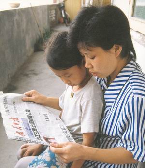 梁伟/被救女孩小洁与母亲正在阅读本报关于北江三勇士的报道梁伟摄