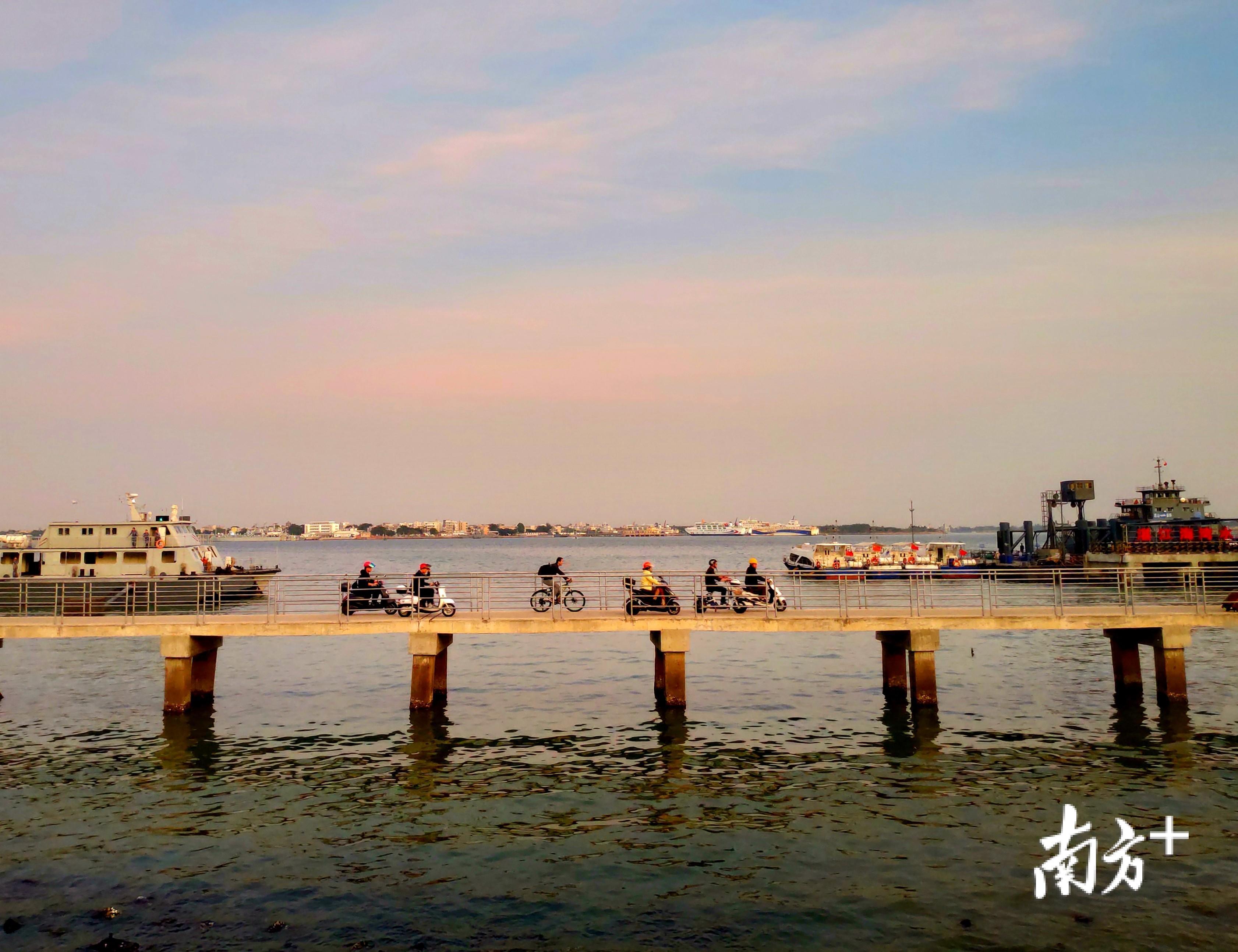 12月4日傍晚时分，湛江市海滨渡口，市民赶轮渡下船后骑车从码头上的栈桥回家。陈永锋 摄