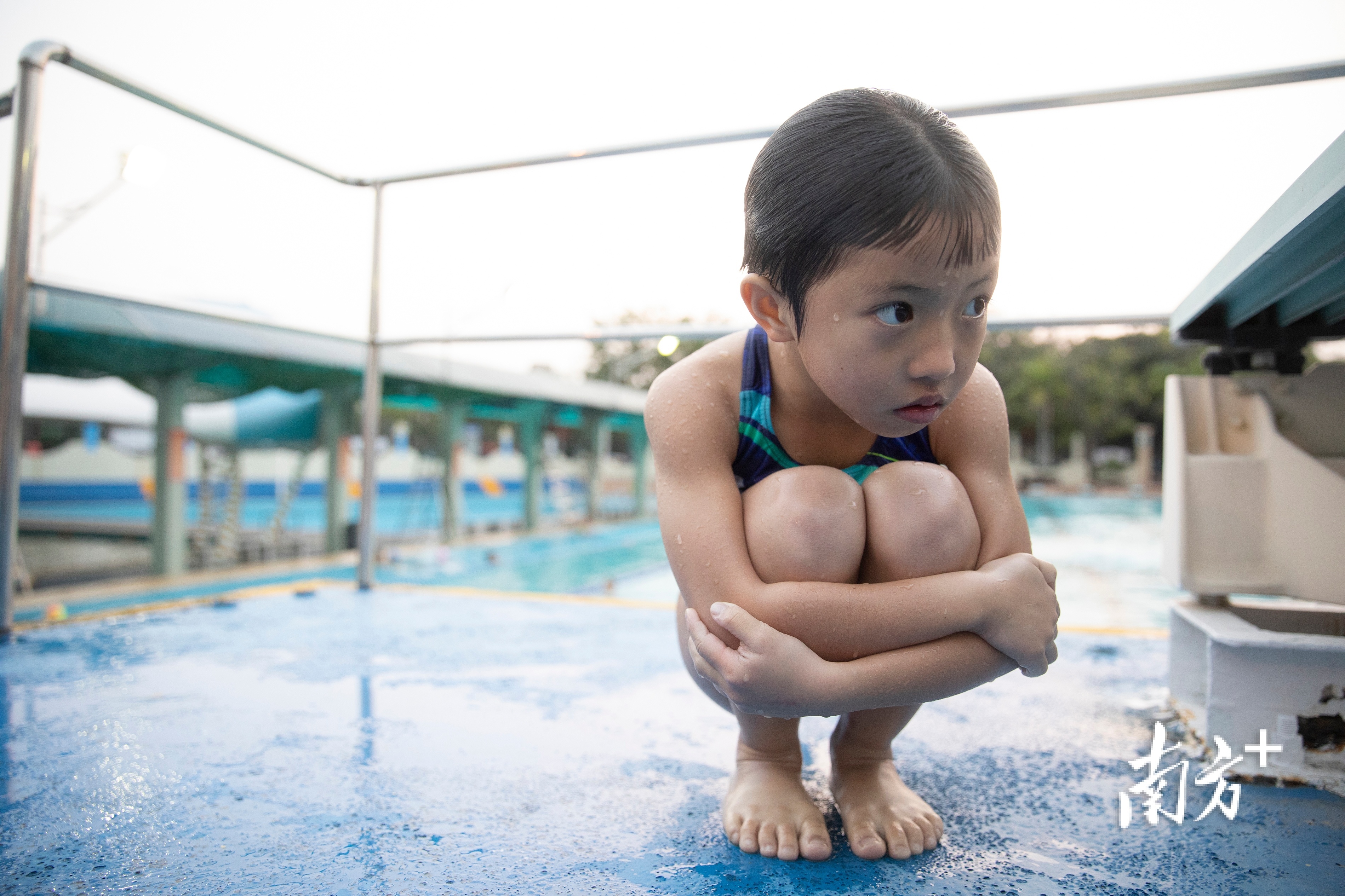 湛江市跳水运动学校，水温有些低，一名从泳池上岸的孩子抱紧身体。