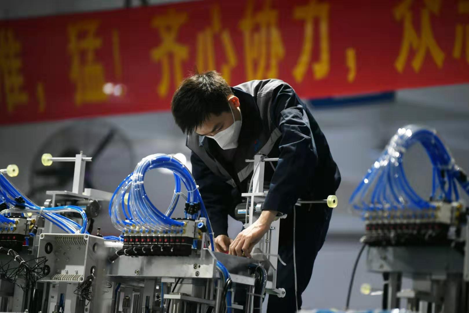 东莞快裕达自动化设备有限公司口罩机生产线上,工人正在调试机器.