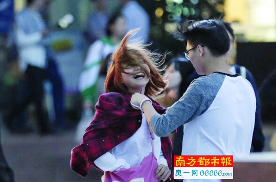 昨晚,起风了,天河城北门,一名男子为女友披上衣服.