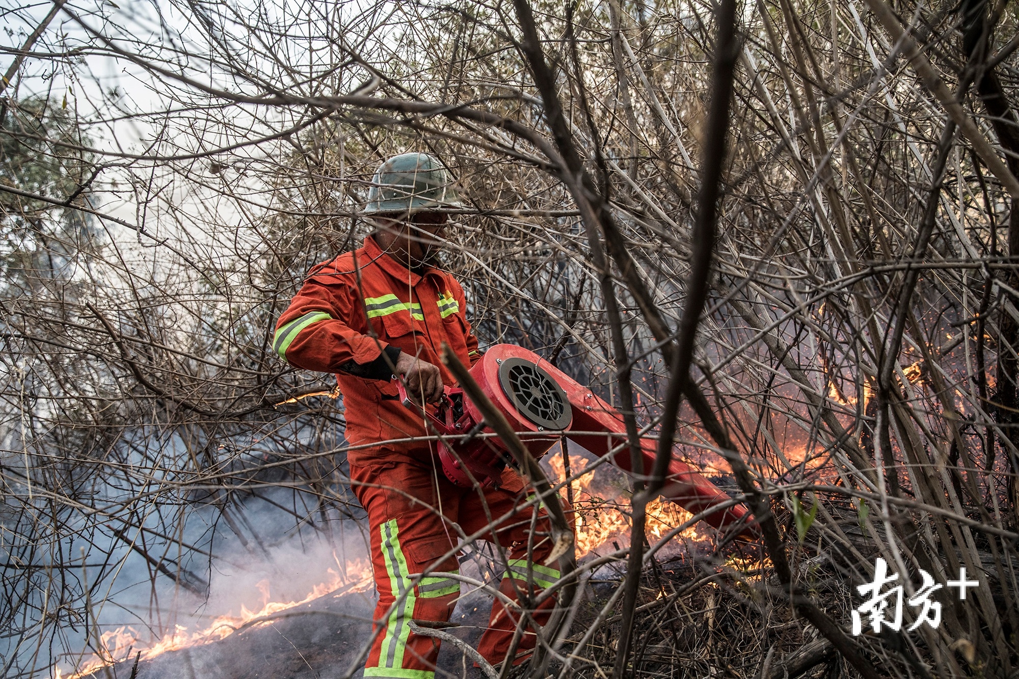 副队长陈传东用鼓风机将火苗熄灭,到处都是干枯的灌木丛.